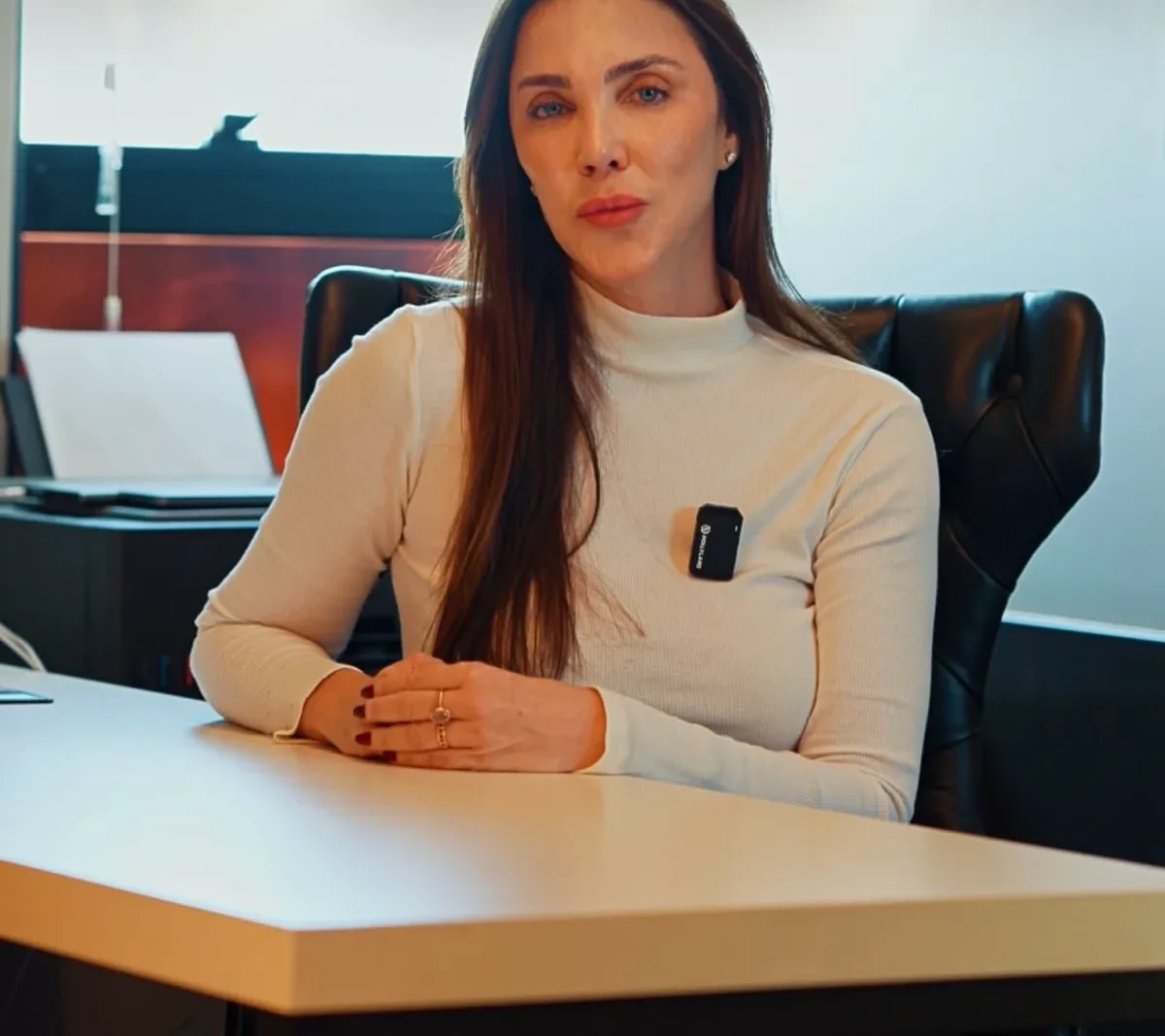 Dra. Tati Clementino em seu consultório, sentada à mesa de atendimento